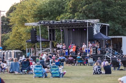 People facing towards and outdoor stage ready for music concert in the park 